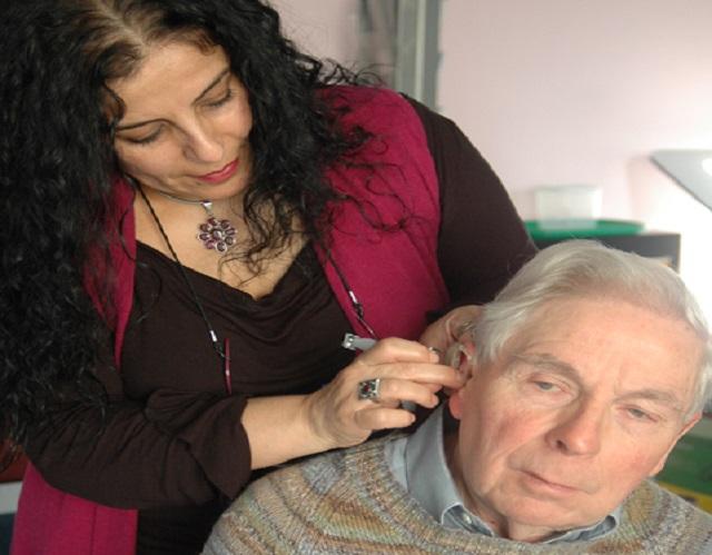 Lady helping man with hearing aid