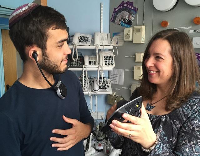 Trained professional showing young man with hearing loss how to use specialist equipment